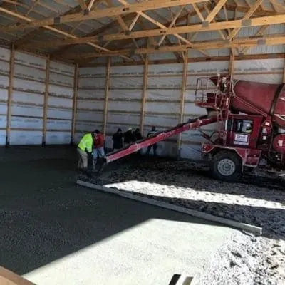 Concrete being placed from a mixer truck inside a pole barn